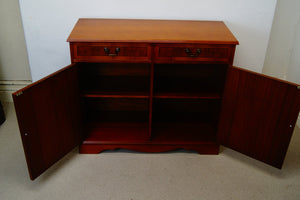 A golden Yew console table with two drawers at the top and a cupboard below