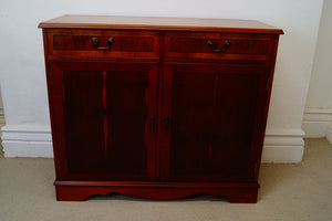 A golden Yew console table with two drawers at the top and a cupboard below