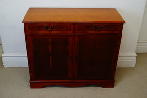 A golden Yew console table with two drawers at the top and a cupboard below