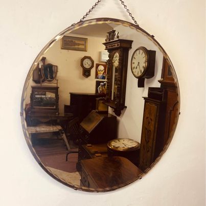 A large circular bevelled edged mirror with its original hanging chain circa 1930