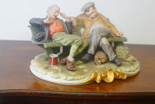 Load image into Gallery viewer, A splendid large porcelain Capodimonte sculpture representing two drunken tramps sat on a bench