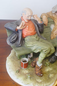 A splendid large porcelain Capodimonte sculpture representing two drunken tramps sat on a bench